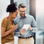 Two colleagues happily reviewing documents together in an office.