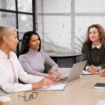Three businesswomen engaged in a meeting around a conference table.