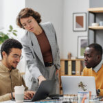 Three colleagues collaborating on a project around a laptop in an office.